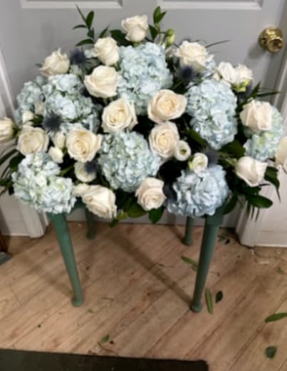 Blue hydrangeas and white roses arranged on a small table.