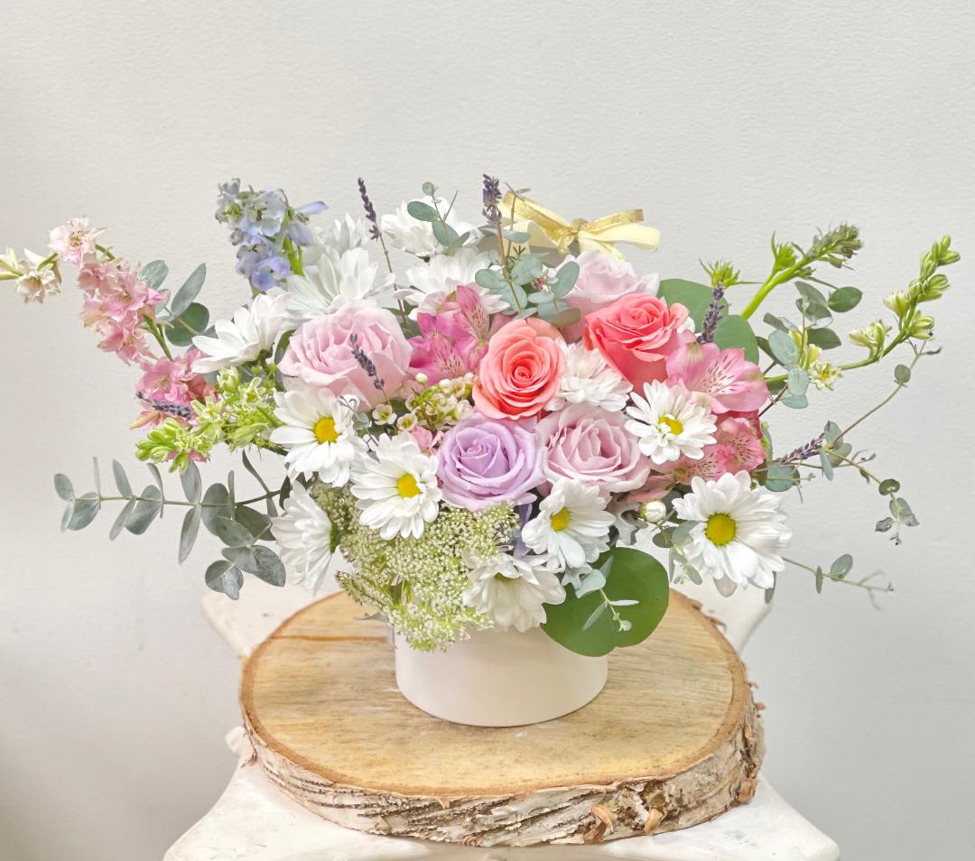 Pastel bouquet of roses and daisies in a white container