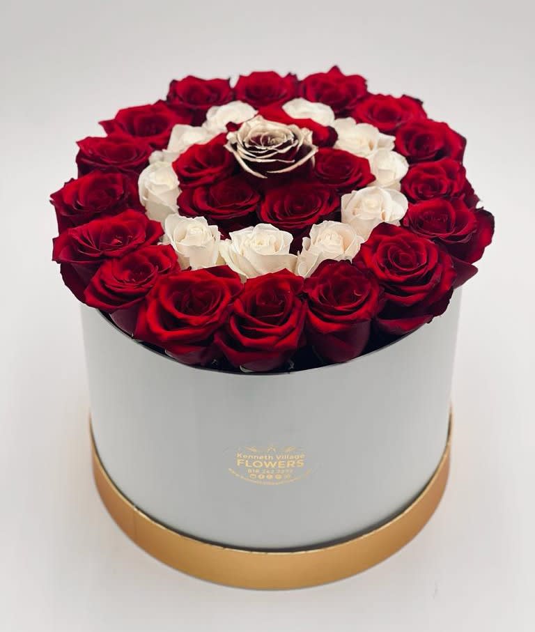 Red and white roses arranged in a round hat box