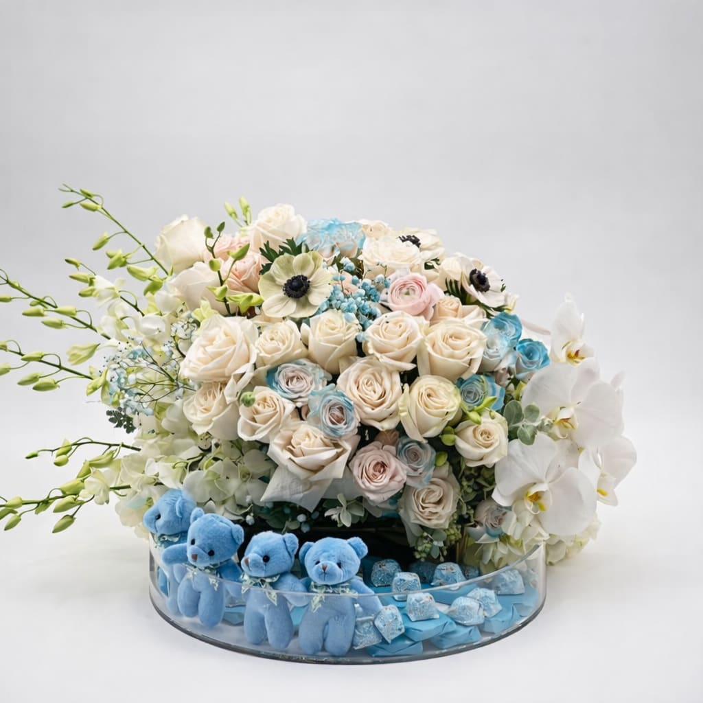 Bouquet of white and pastel roses with orchids in a glass bowl, with blue teddy bears below.