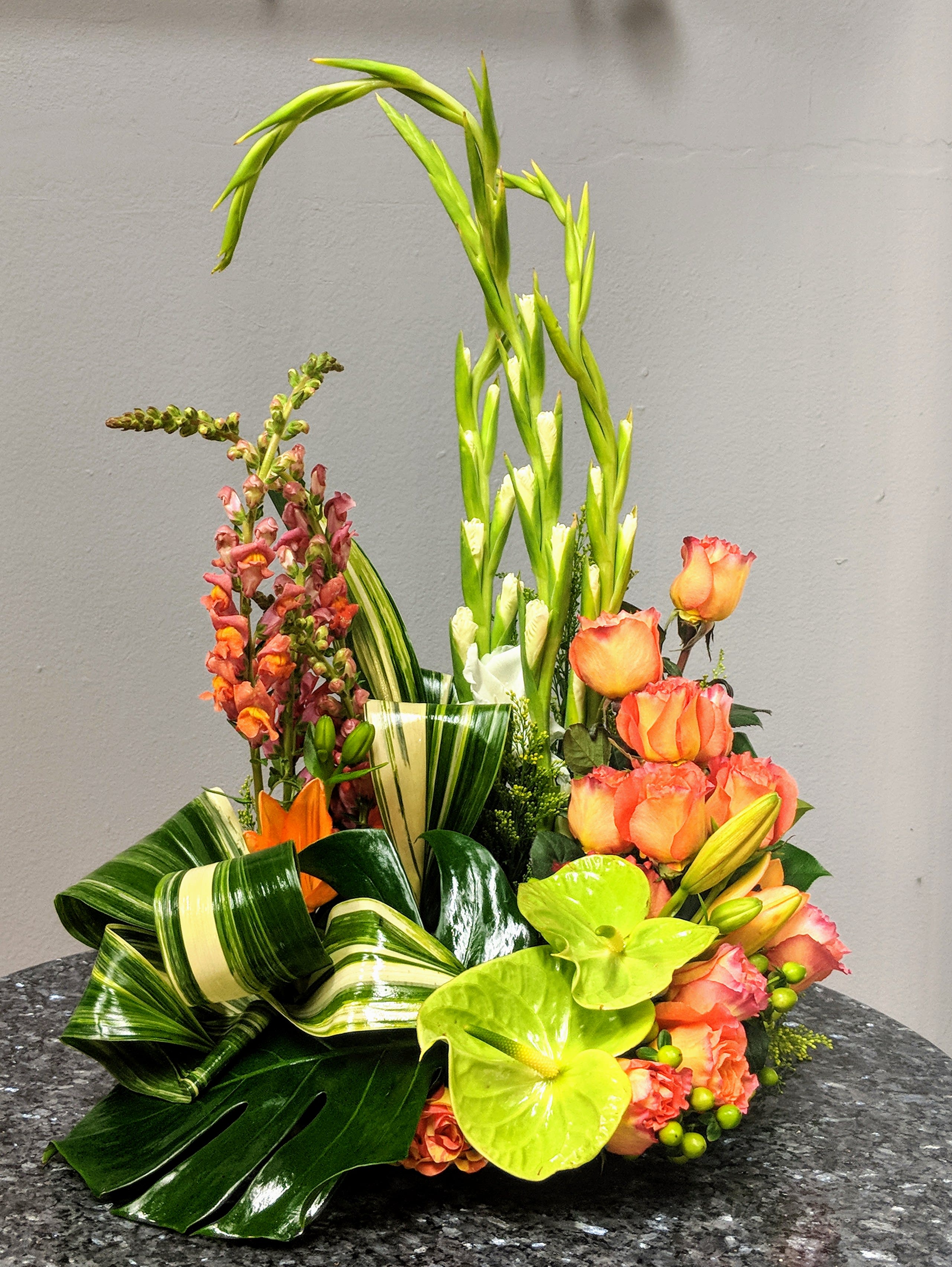Tropical floral arrangement with orange roses and green anthuriums