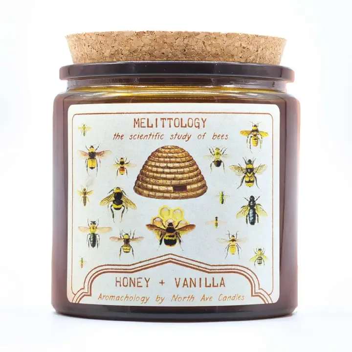 Aromachology Bee Candle - Melittology - the scientific study of bees  See what all the buzz is about!  Honey and Vanilla A cozy gourmand scent - warm, comforting vanilla bean with a kiss of rich, sweet honey  Label art featuring original, in-house artwork inspired by vintage science diagrams showcasing bees and honeycomb  Made with coconut-soy wax and poured into an amber cork-topped apothecary style jar made from recycled glass. Double wicked to ensure an even burn and strong scent throw.  13oz | 80+ burn hours jar dimensions 3.5" diameter 3.5" tall (before cork) finished candle with cork measures approx 4" tall 