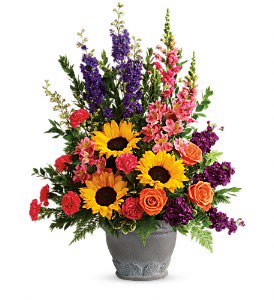Tall mixed arrangement with sunflowers, roses, and bright blooms in a gray pot