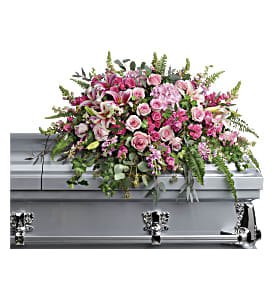 Pink and white casket spray with roses and lilies on a silver casket