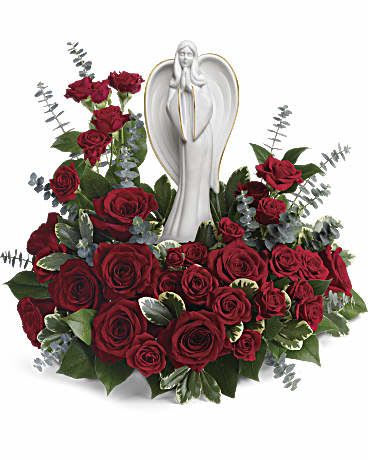Sympathy arrangement of dark red roses surrounding a white angel figurine
