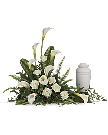 White calla lilies and roses arranged beside a white memorial urn