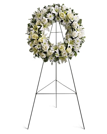 Standing wreath of white lilies, roses, and mums on a metal easel
