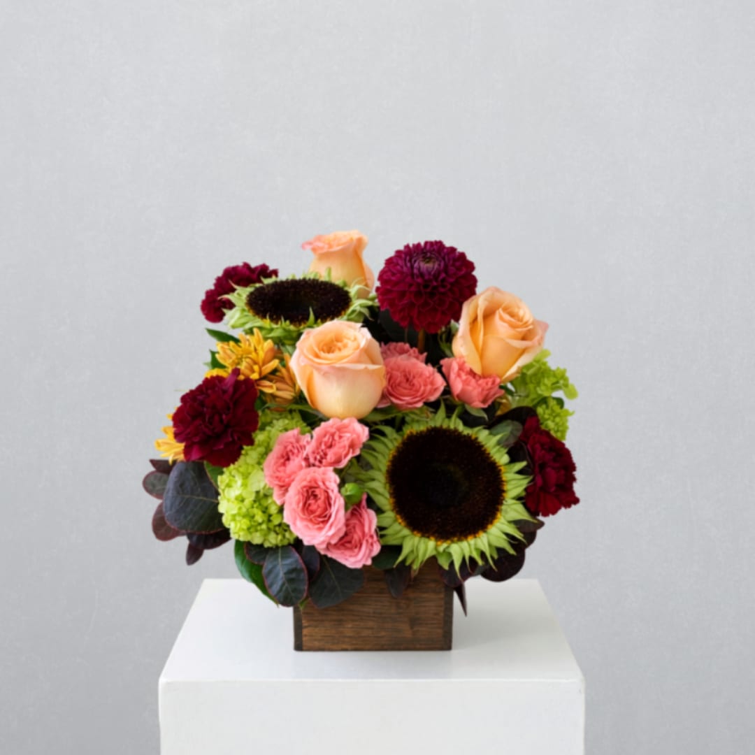 Mixed bouquet in a wooden box with peach roses, sunflowers, and burgundy blooms