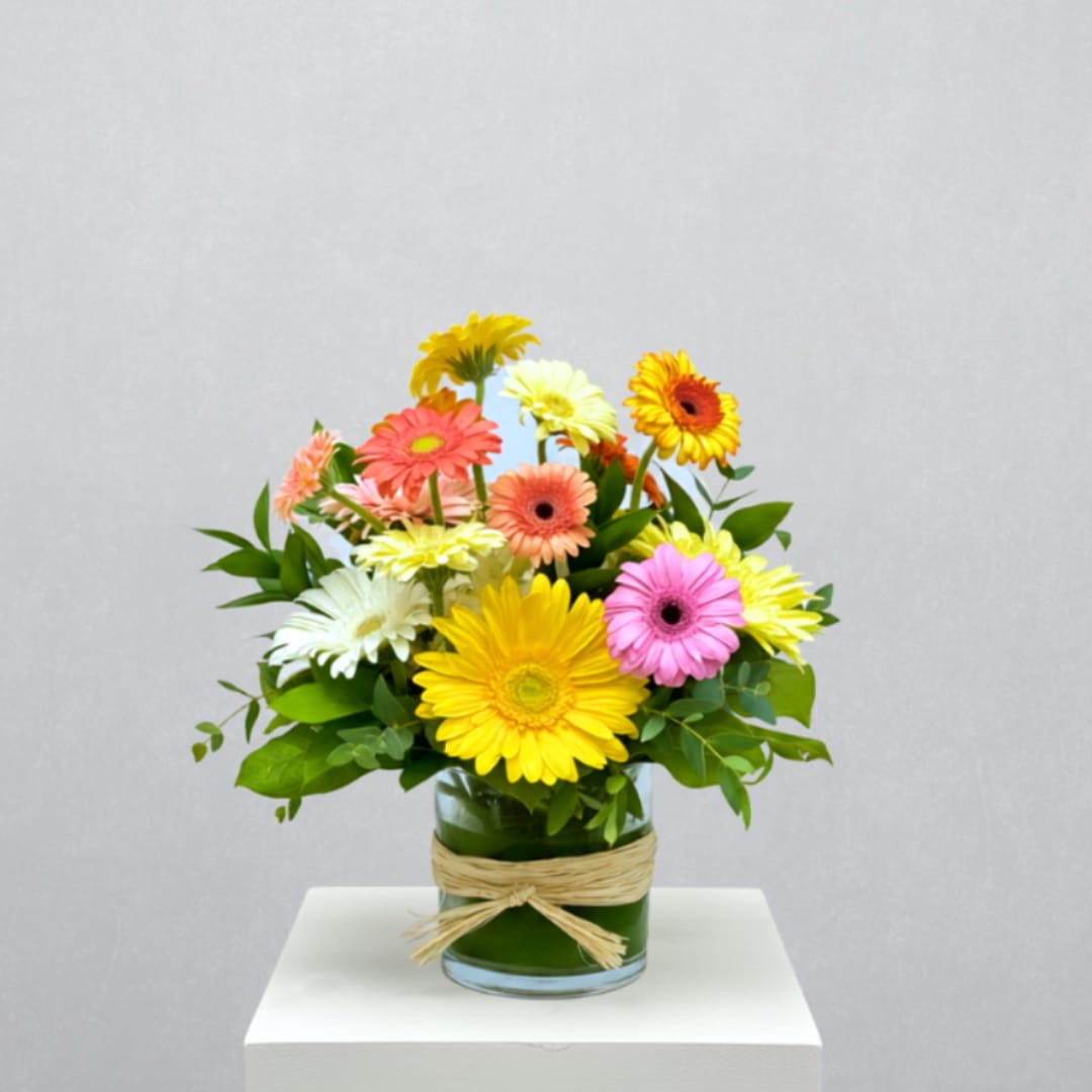 Colorful gerbera daisy bouquet in a glass vase with raffia tie