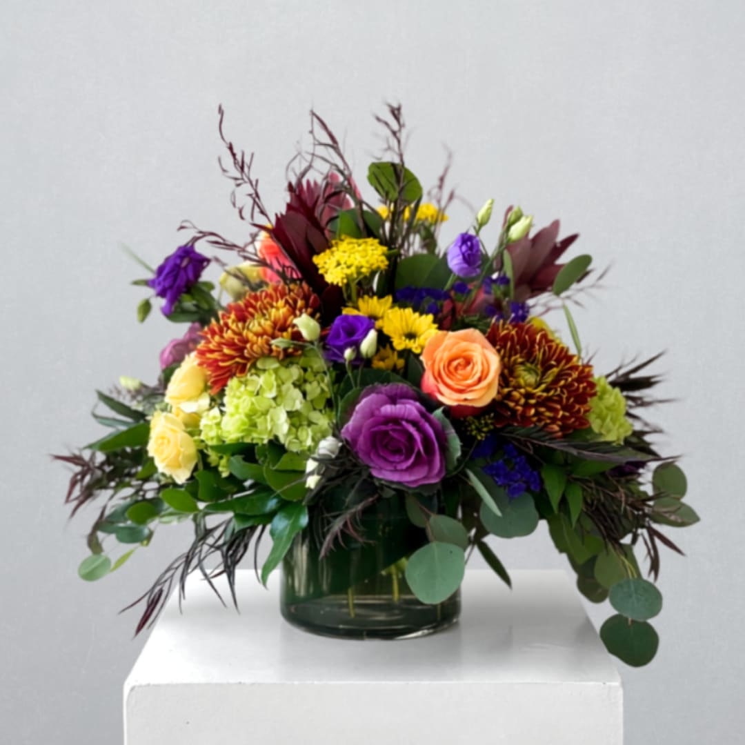Mixed bouquet of roses, chrysanthemums, and hydrangea in a glass vase