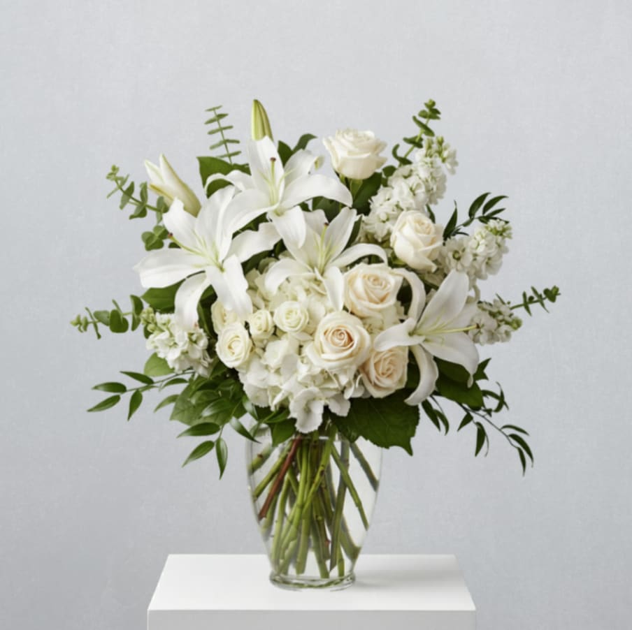 White lilies and roses arranged in a clear glass vase