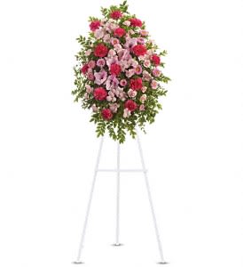 Oval standing spray of pink and red flowers on a white metal easel