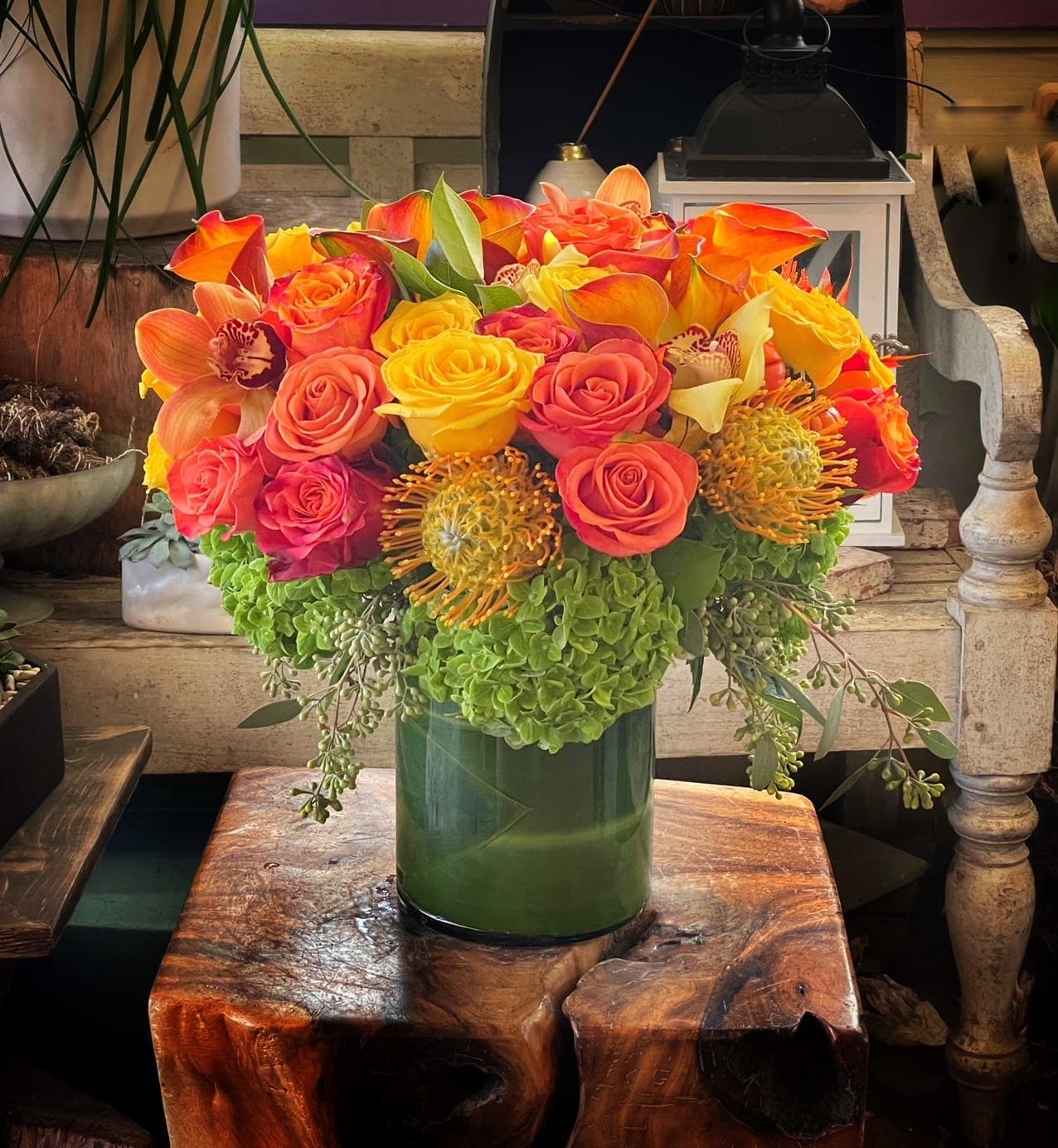 Bright bouquet of orange, yellow, and pink flowers in a green vase