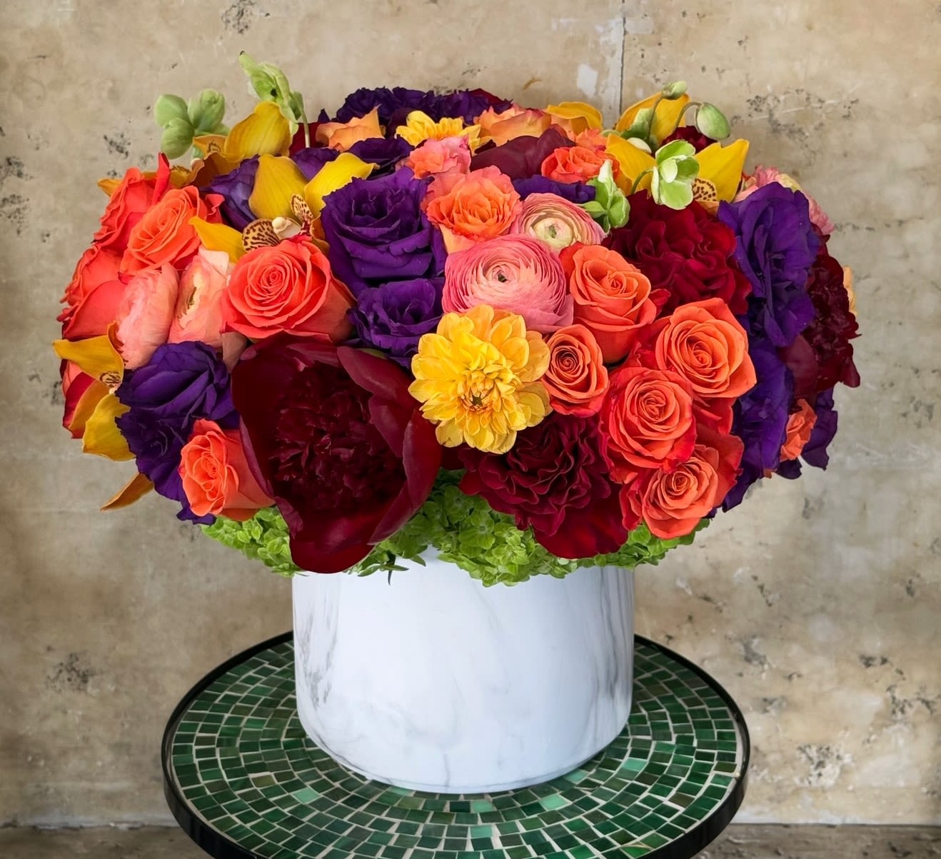 Bright mixed bouquet in a white vase with roses and ranunculus