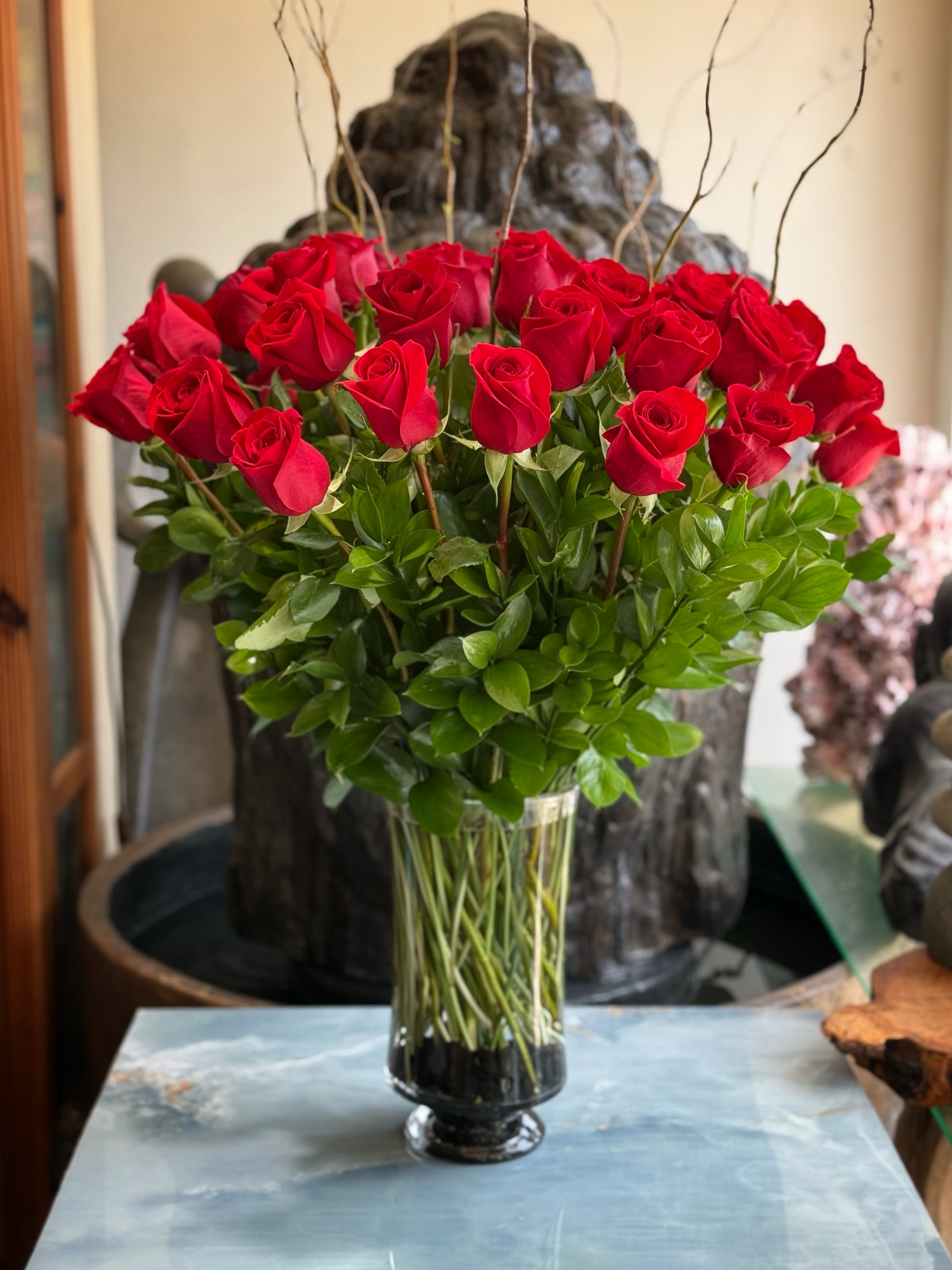 Red roses arranged in a tall glass vase