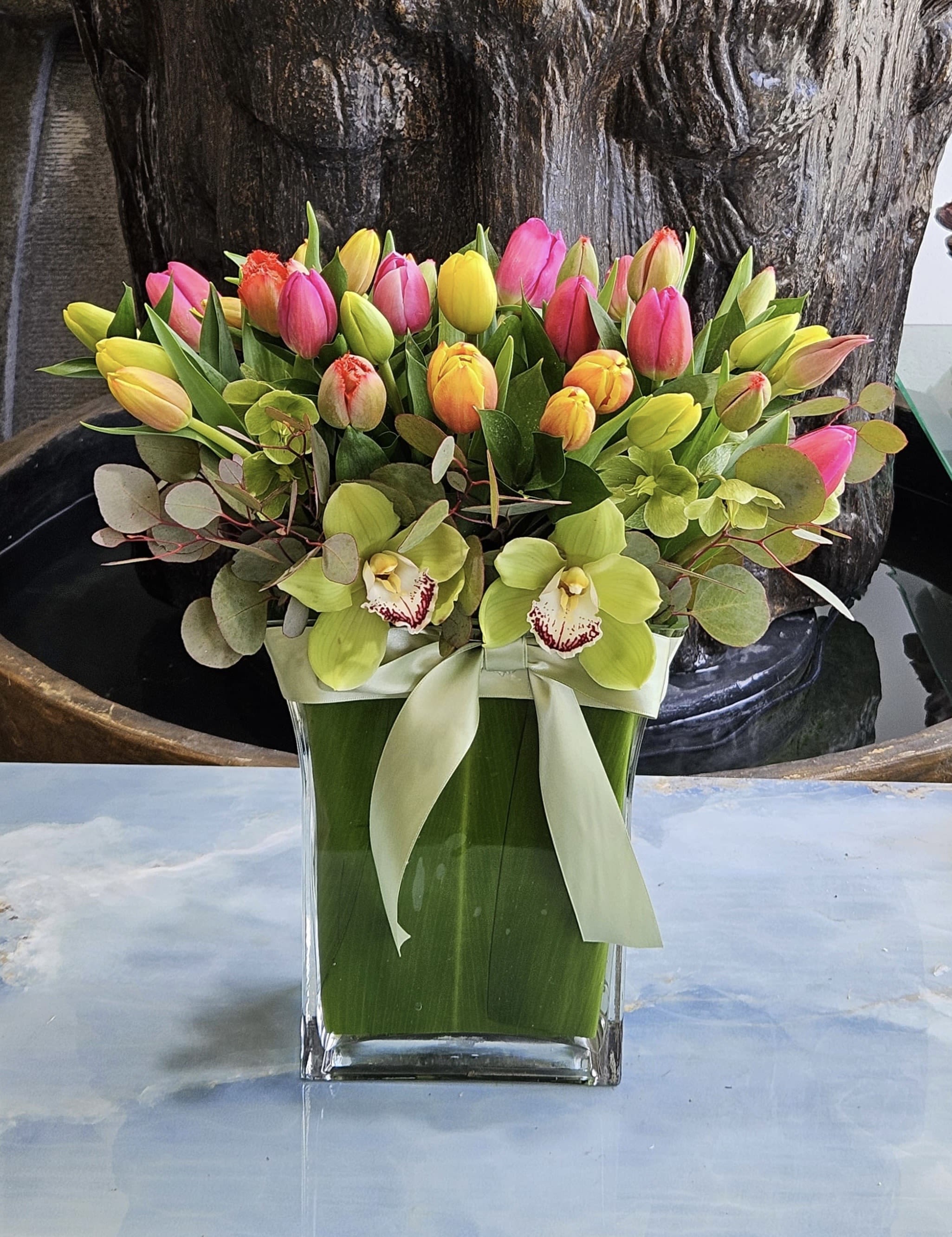 Colorful tulip bouquet with orchids in a glass vase