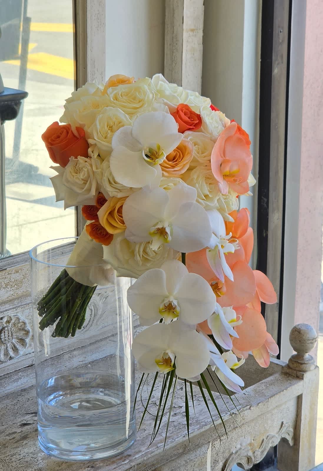 Bouquet of white and peach roses with white orchids in a clear glass vase
