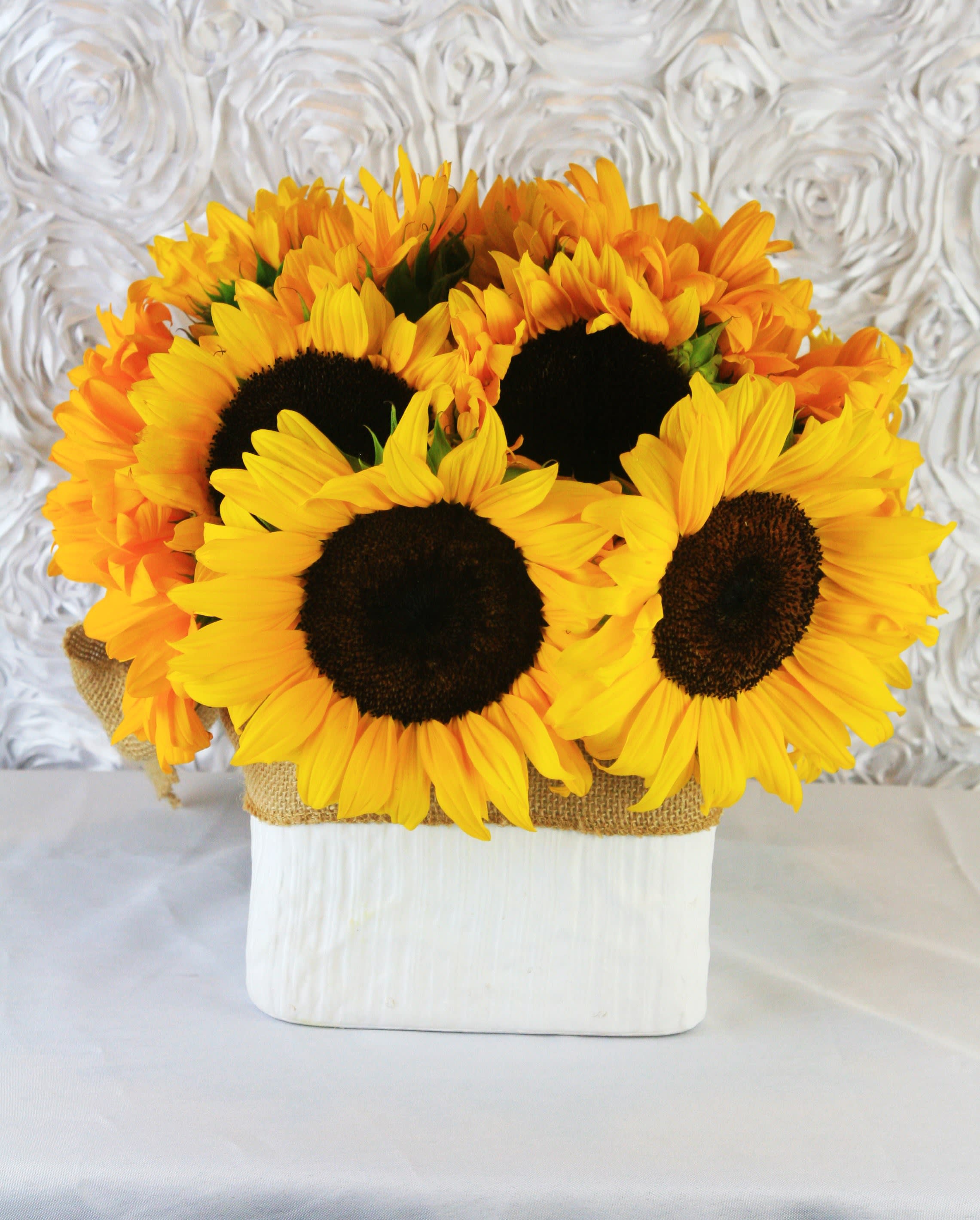 Bouquet of bright yellow sunflowers in a white container