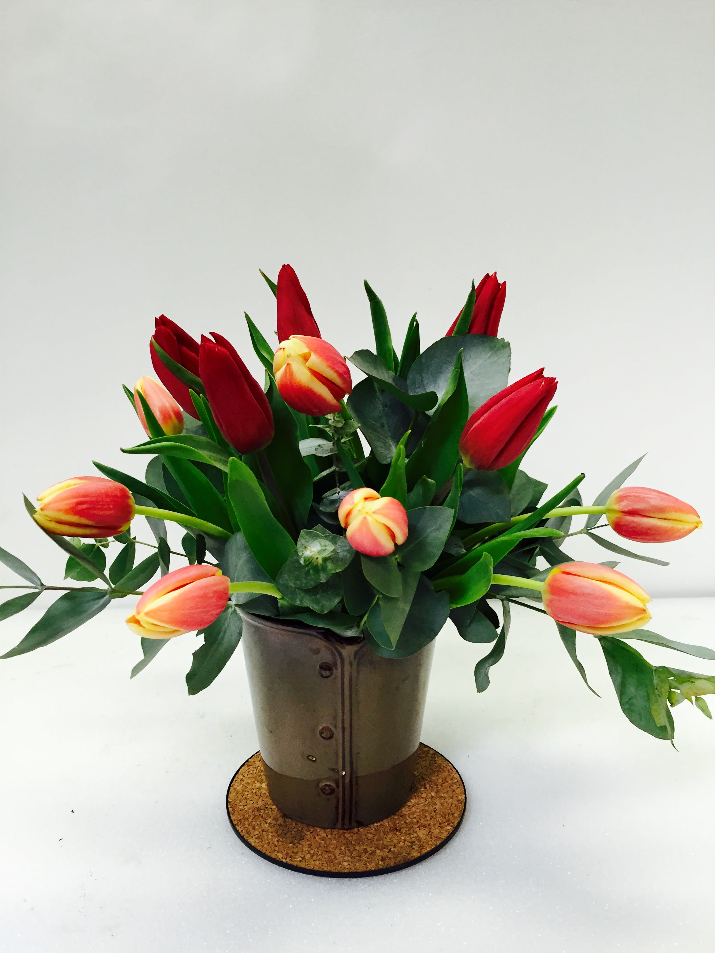 Red and peach tulips arranged in a metal pot