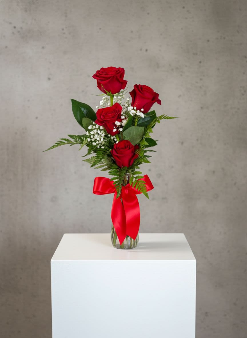 Red roses in a clear glass vase with a red ribbon