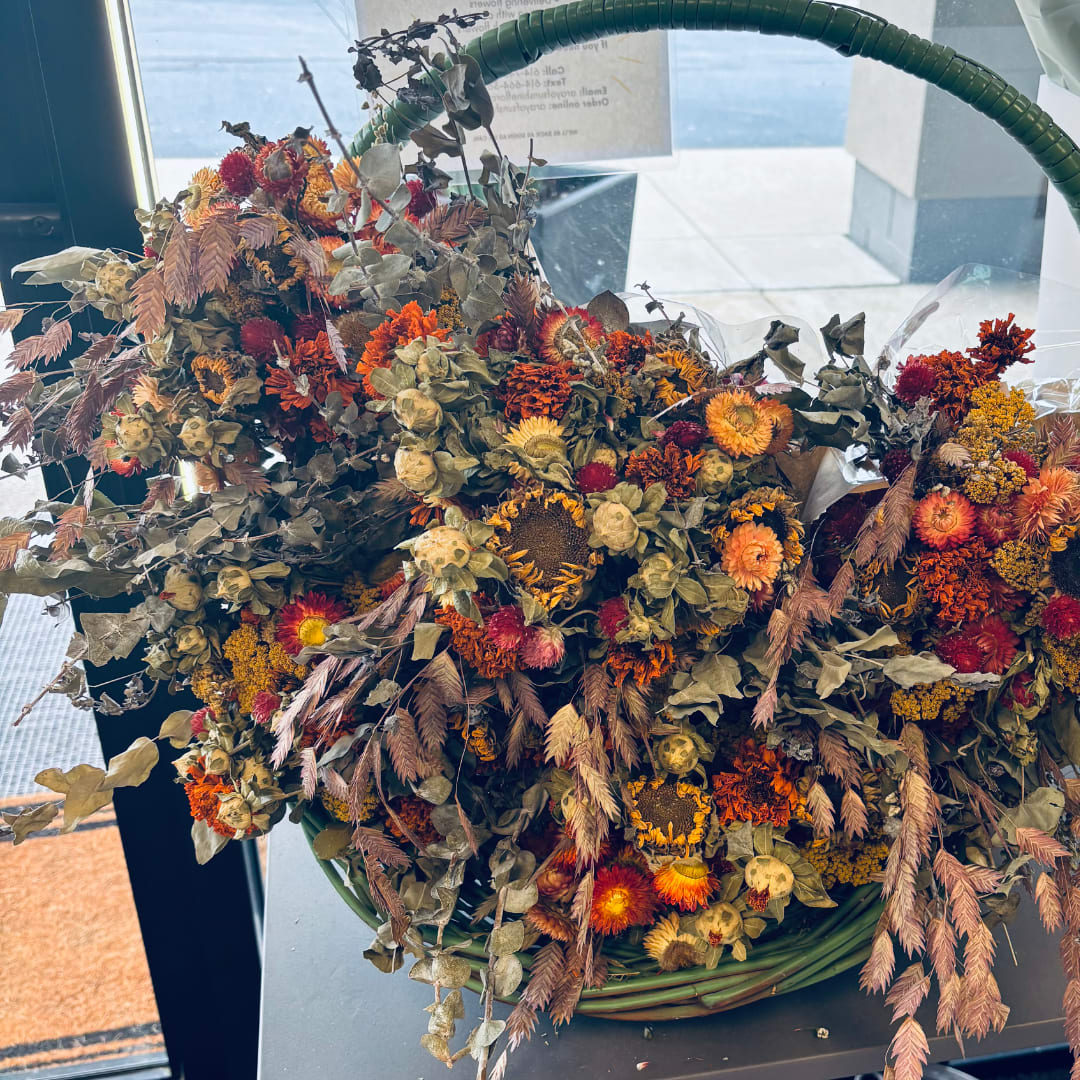 Large autumn bouquet with orange and red dried flowers in a green basket