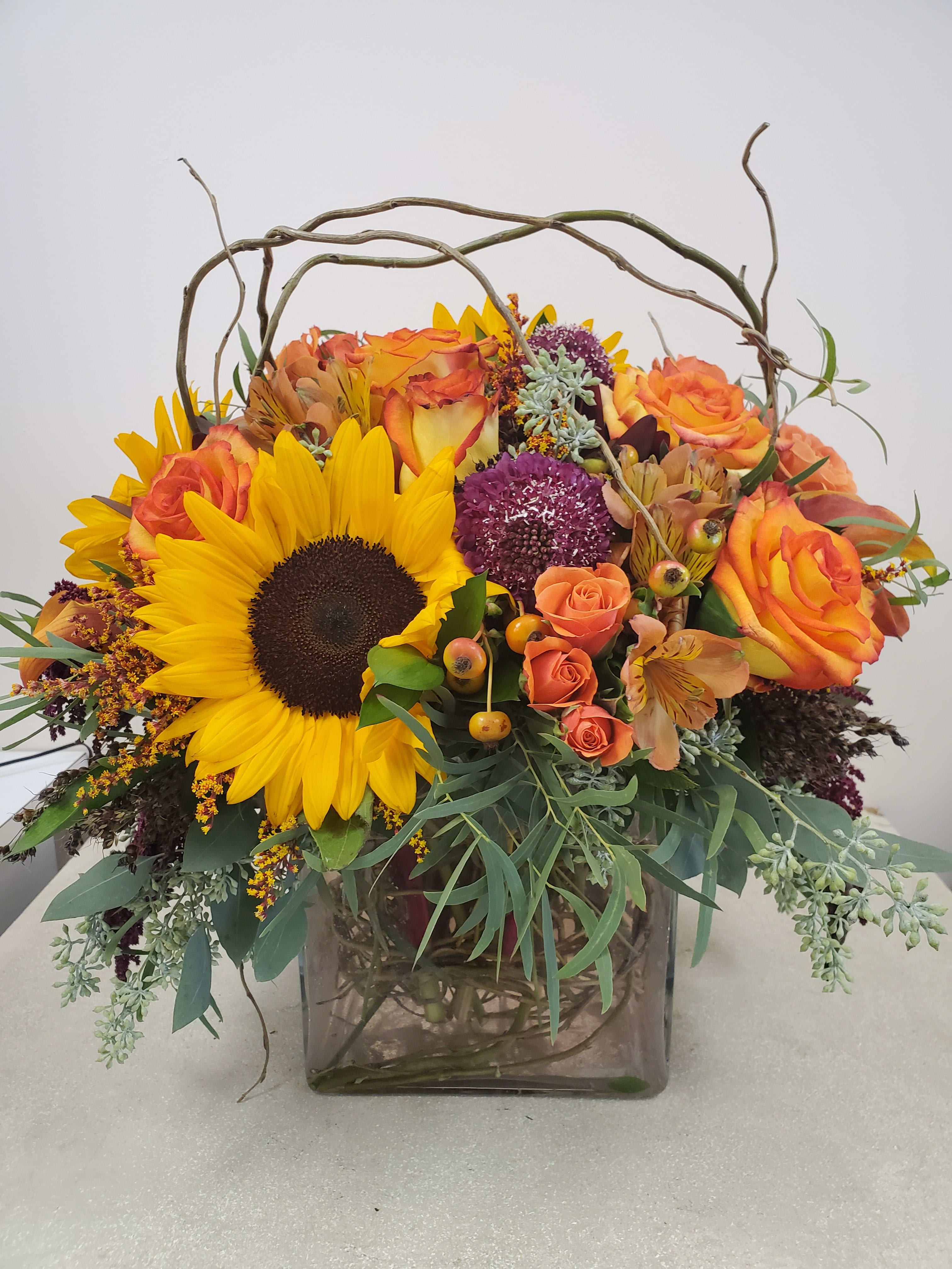 Sunflower Cube - An array of oranges, greens and a touch of burgundy. Includes: Sunflowers, Roses, Spray roses and Greens to complete the rustic look.
