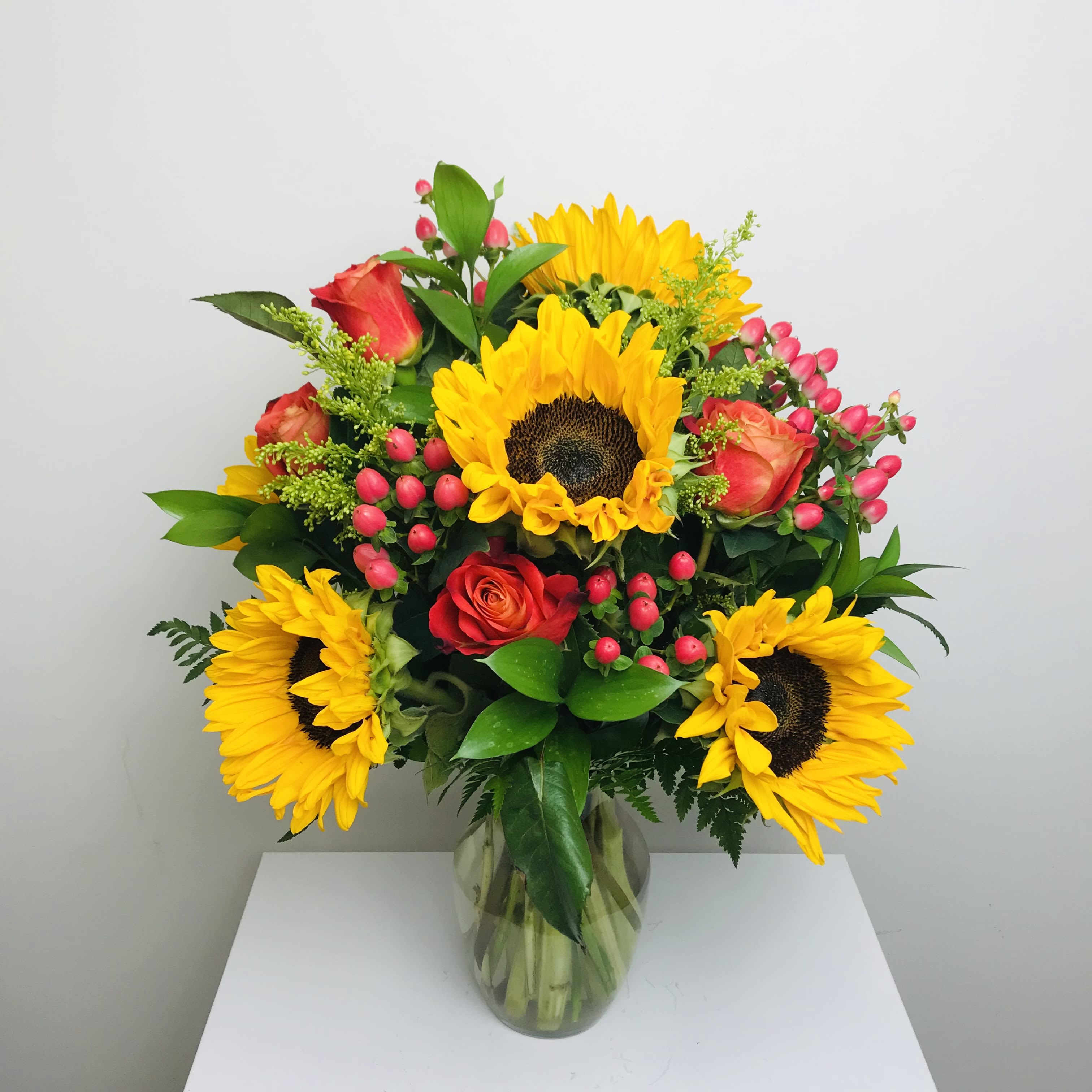 Bouquet of sunflowers and red roses in a clear glass vase