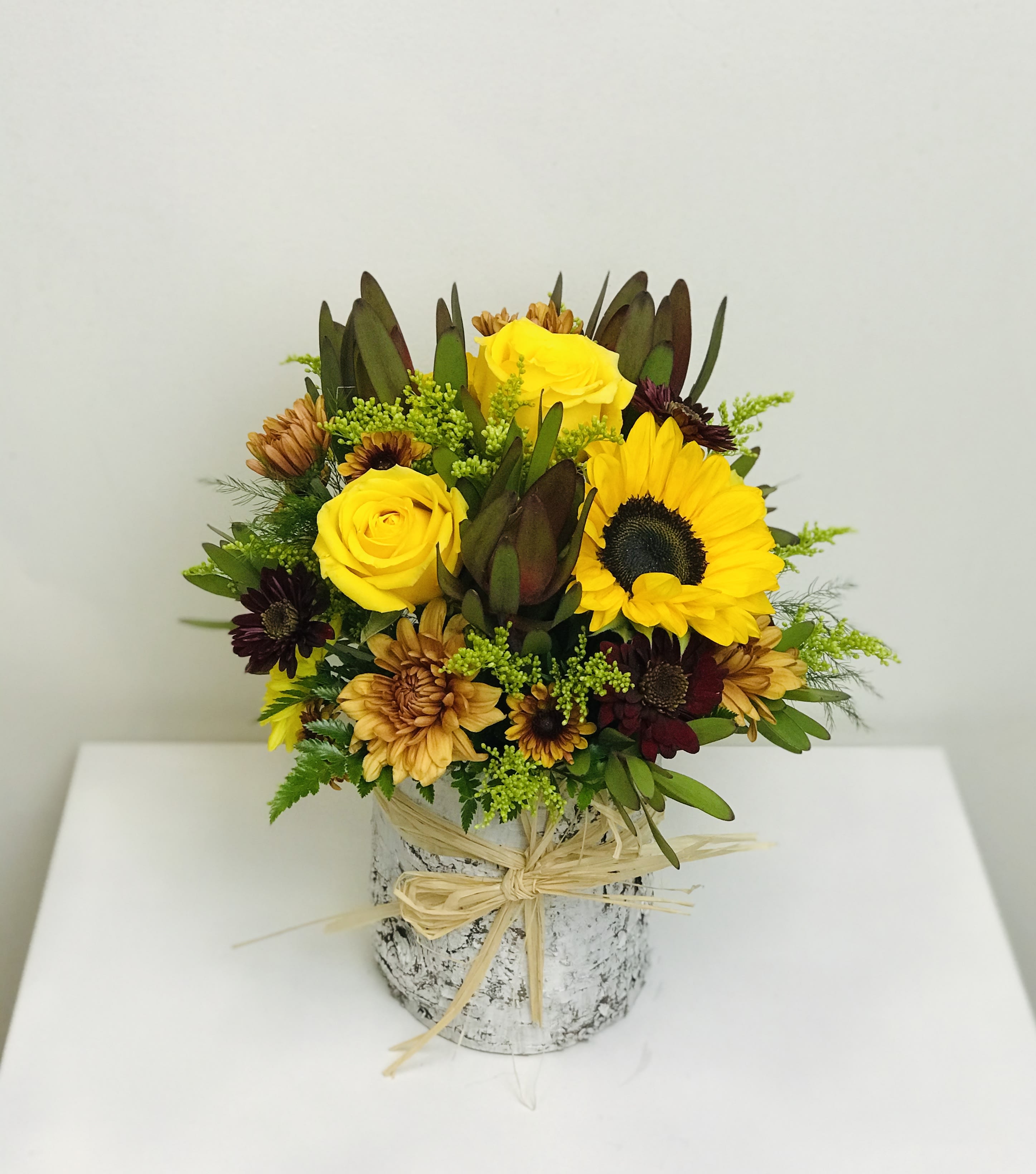 Yellow roses and sunflowers in a rustic wrapped vase arrangement