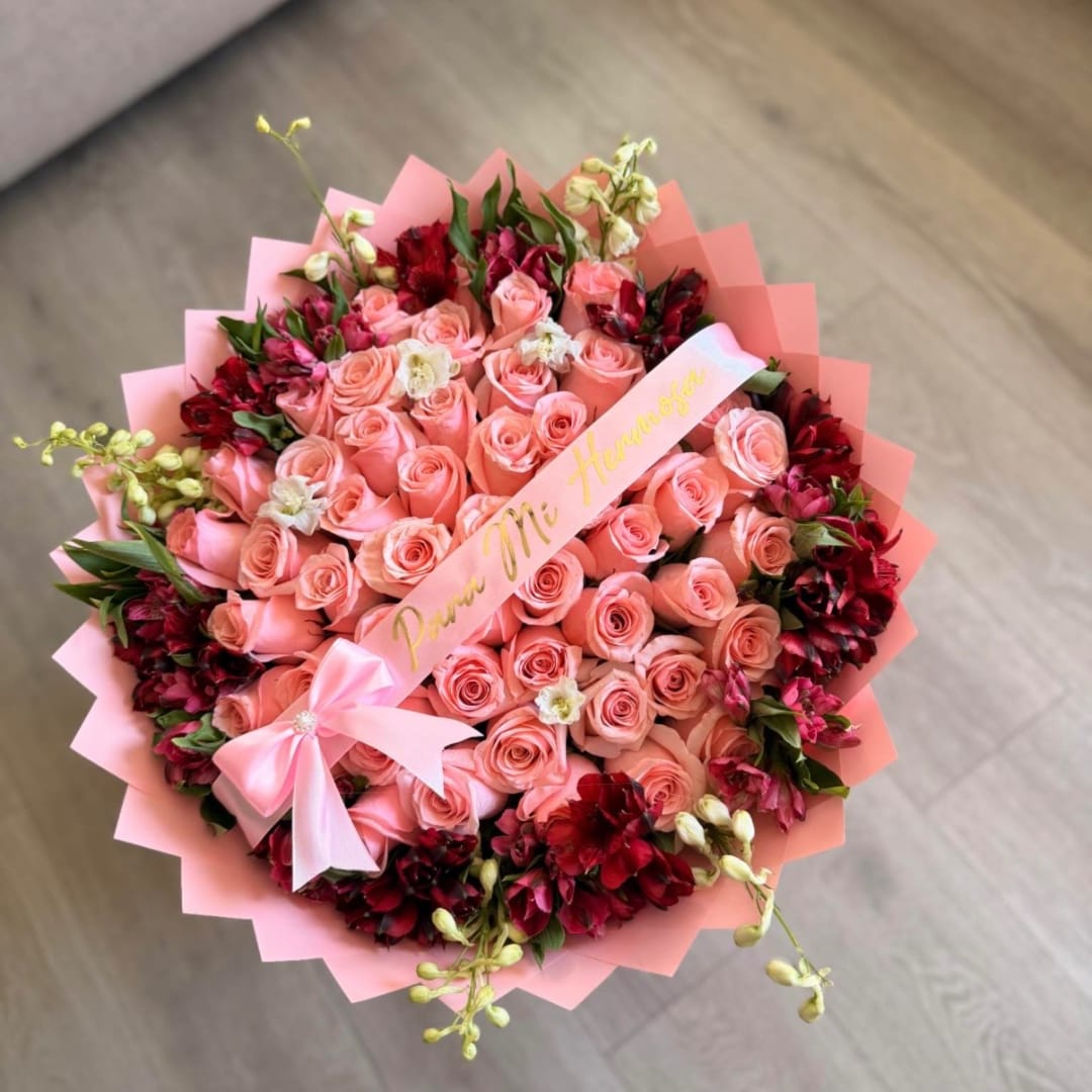Pink rose bouquet with red accent flowers and a ribbon