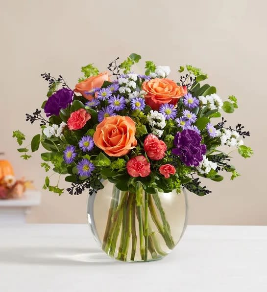 Halloween Delight Bouquet - Bubbling up from a cauldron-like bowl, our Halloween-hued blooms are a true delight. Warm orange roses mix with rich purple carnations for a contrast of color. Lush greenery all around adds texture to this spirited bouquet, capturing everything there is to love about this time of year.