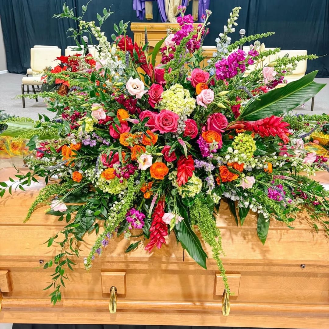 Large colorful floral casket spray with roses and tropical blooms