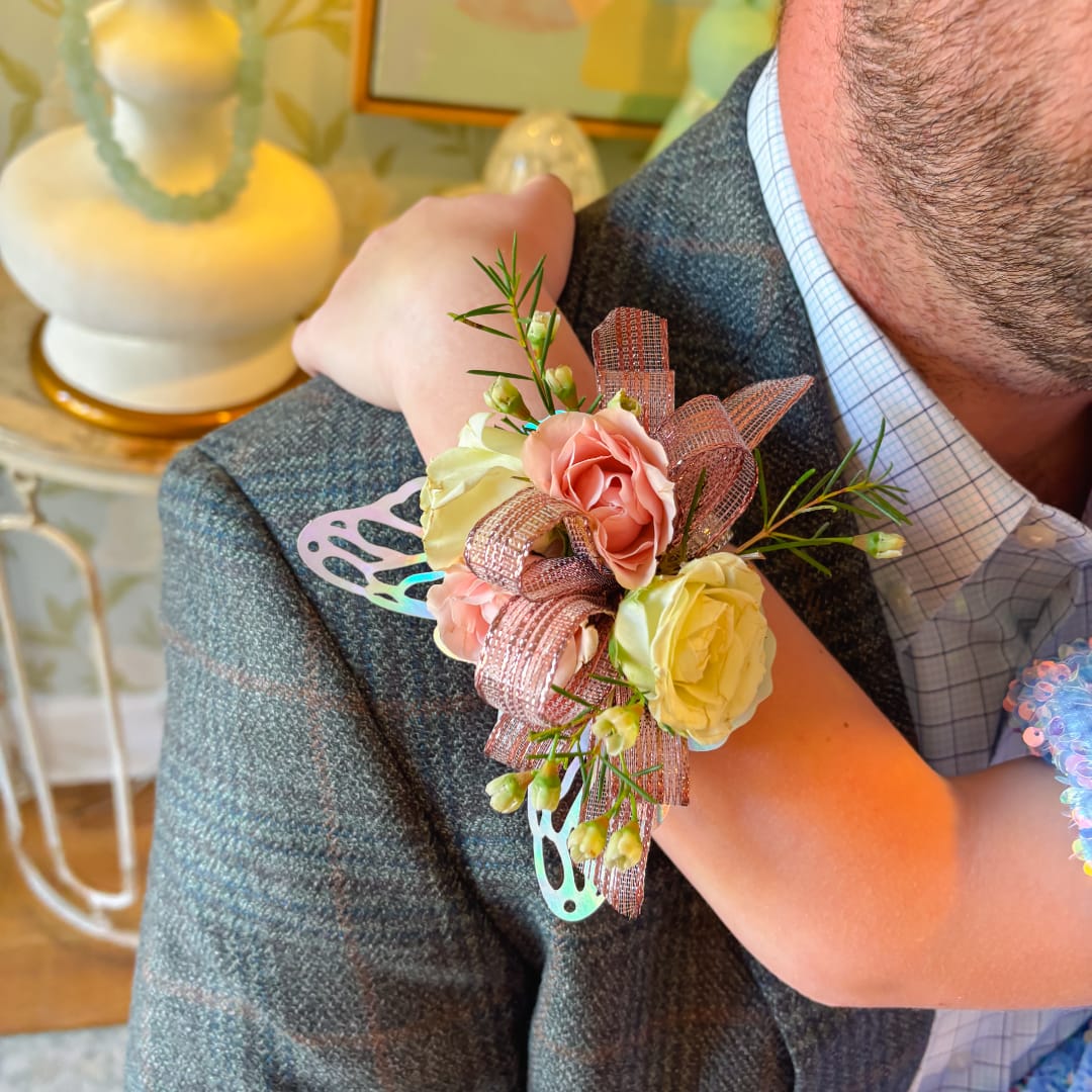 Pink and cream rose corsage on a man's jacket with ribbon