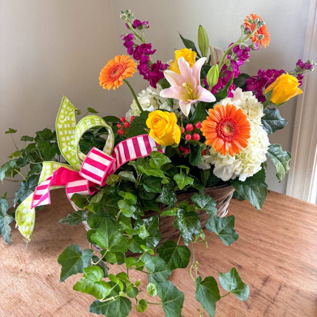 Colorful mixed flower basket with gerberas, roses, lilies, and ribbon