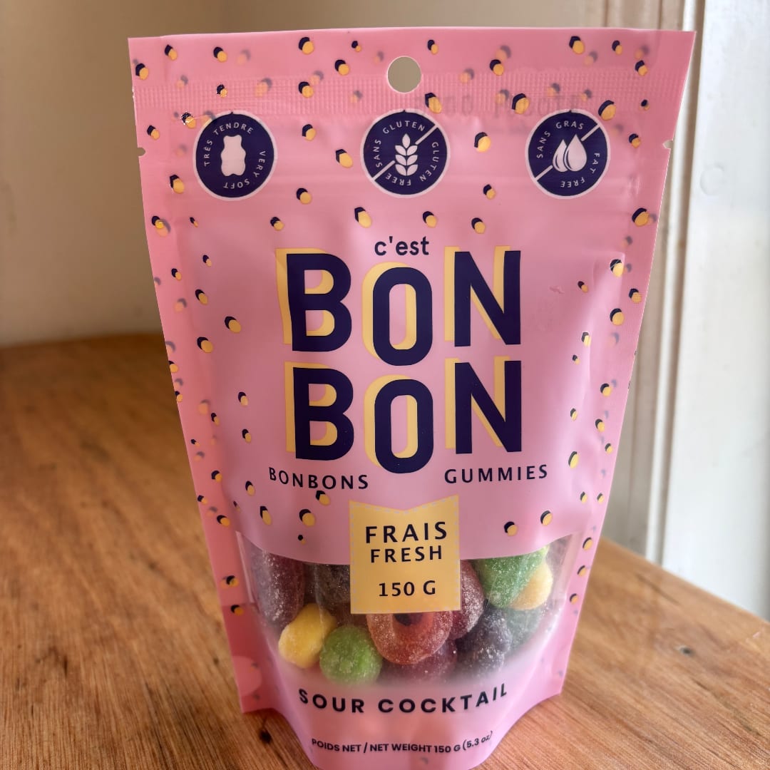 Pink bag of sour cocktail gummies standing on a wooden table