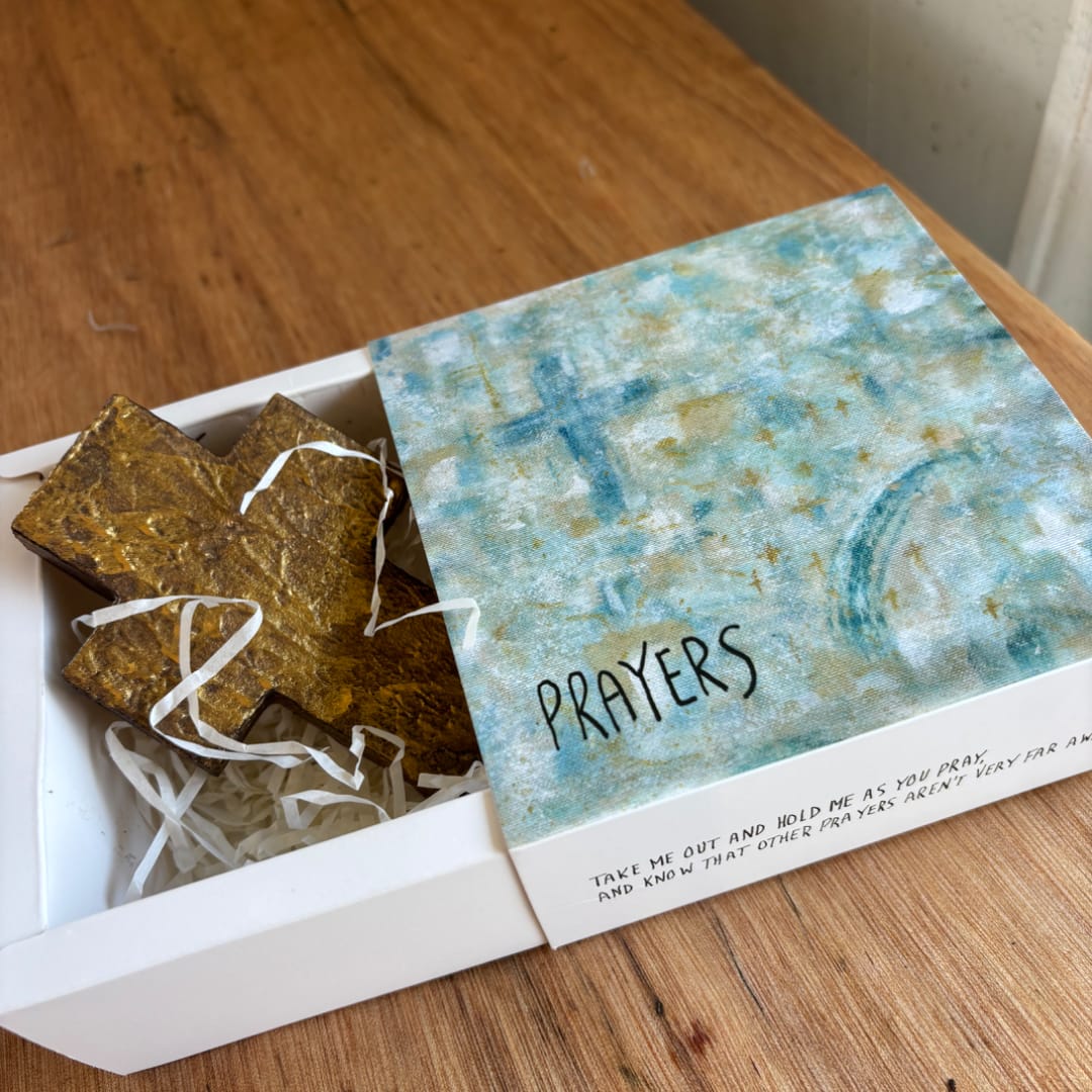 Gift box with a gold cross and a lid labeled "PRAYERS"