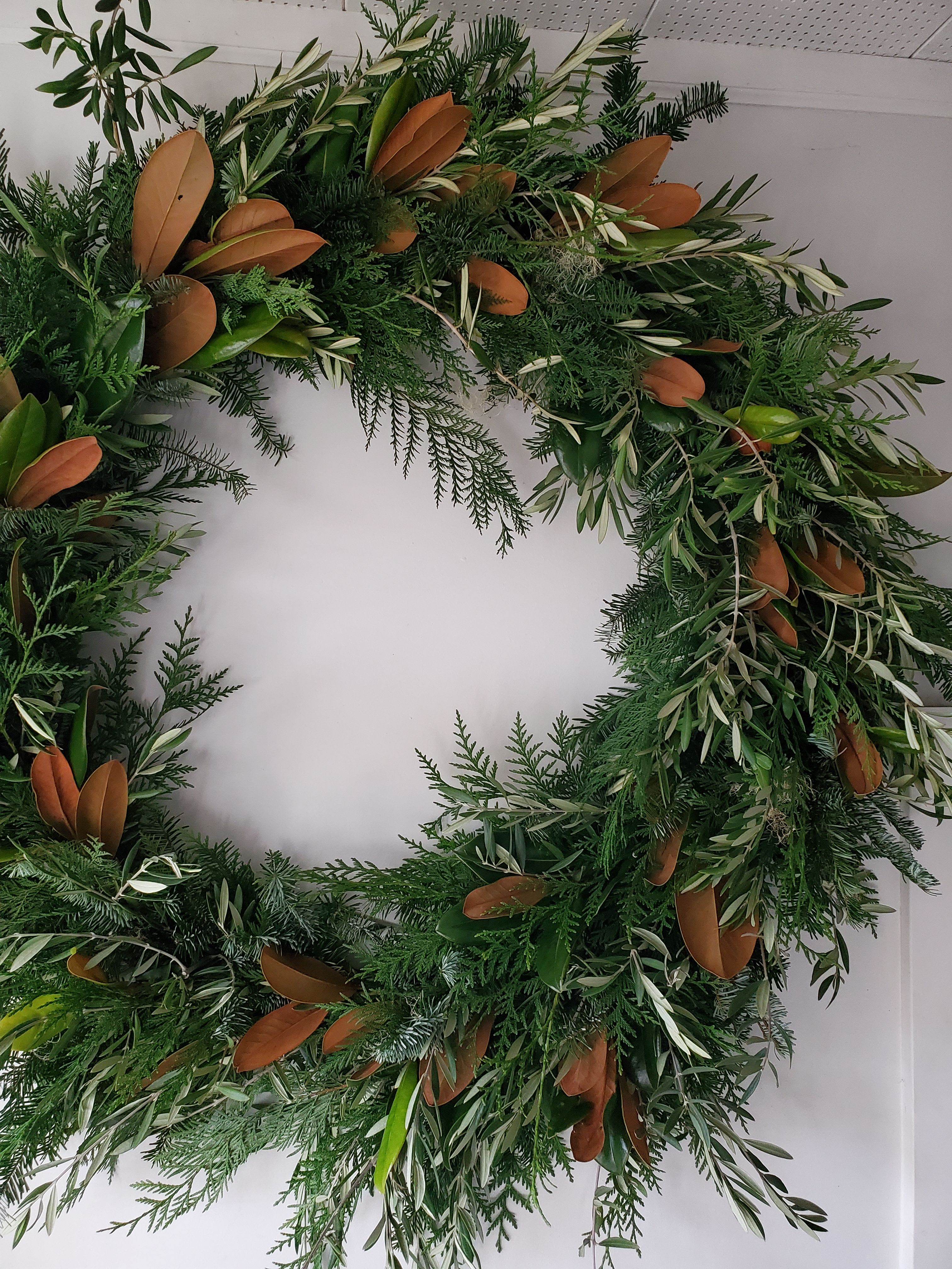 Large green foliage wreath with mixed evergreens and brown-backed leaves