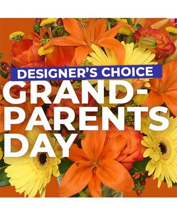 Orange and yellow mixed flower arrangement with a "Designer’s Choice Grandparents Day" sign