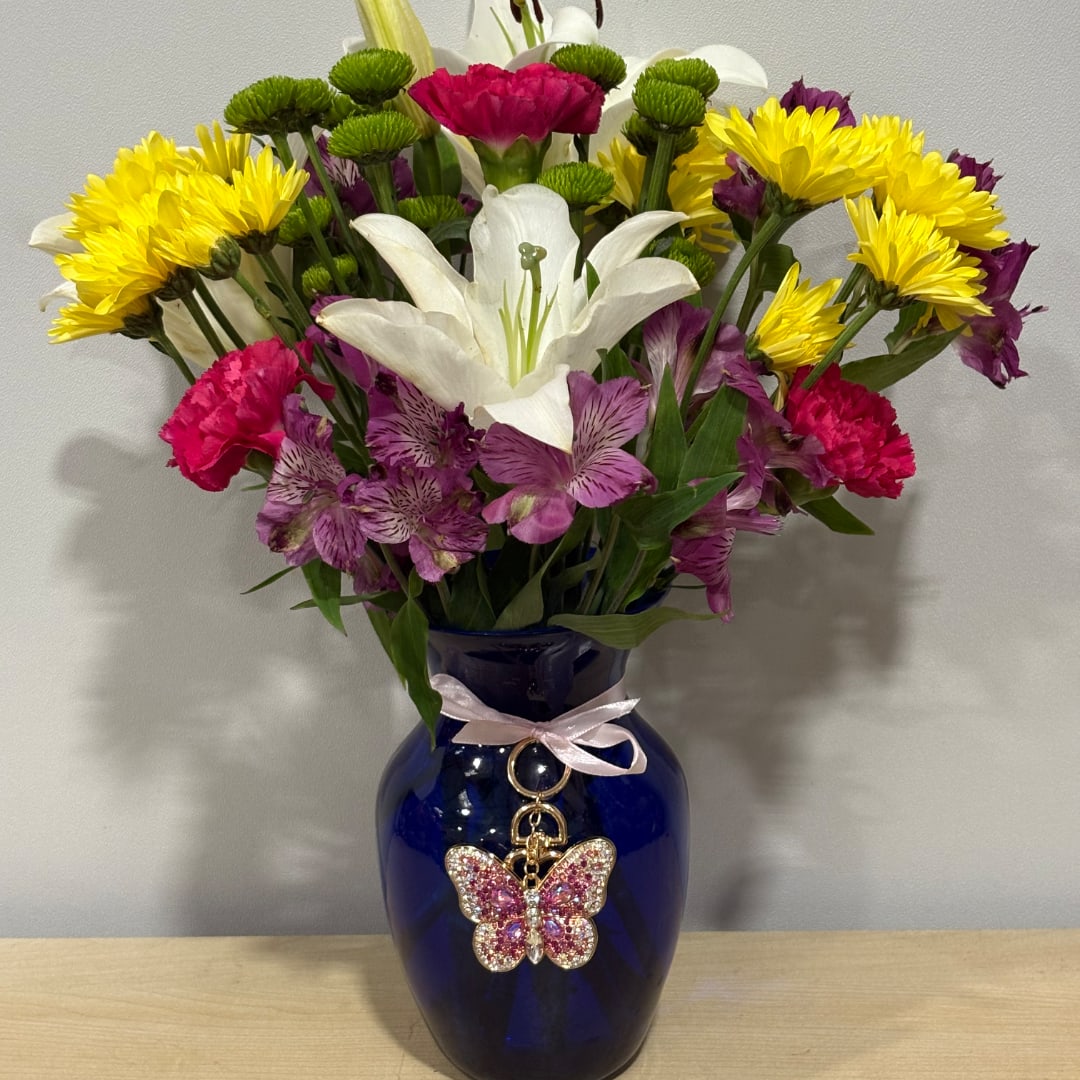 Mixed bouquet with white lily, yellow daisies, pink carnations, and purple alstroemeria in a blue vase