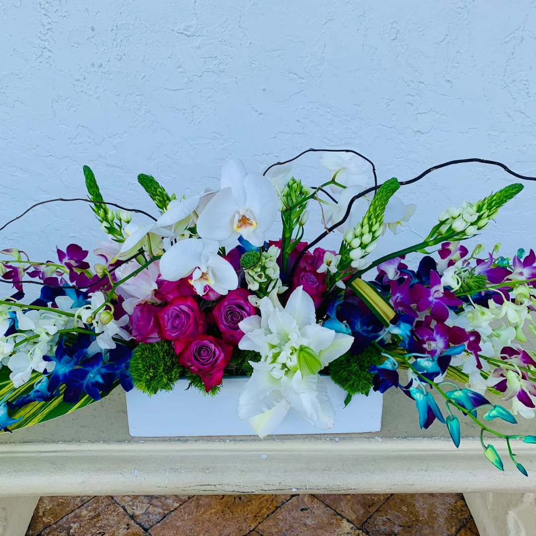Colorful orchid and rose arrangement in a white rectangular vase