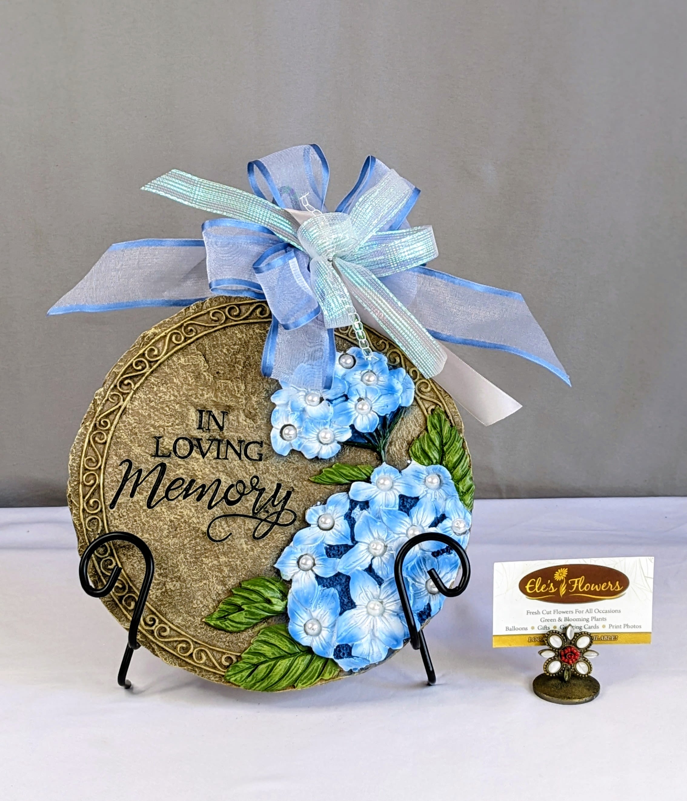 Decorative memorial plaque with blue flowers and ribbon bow
