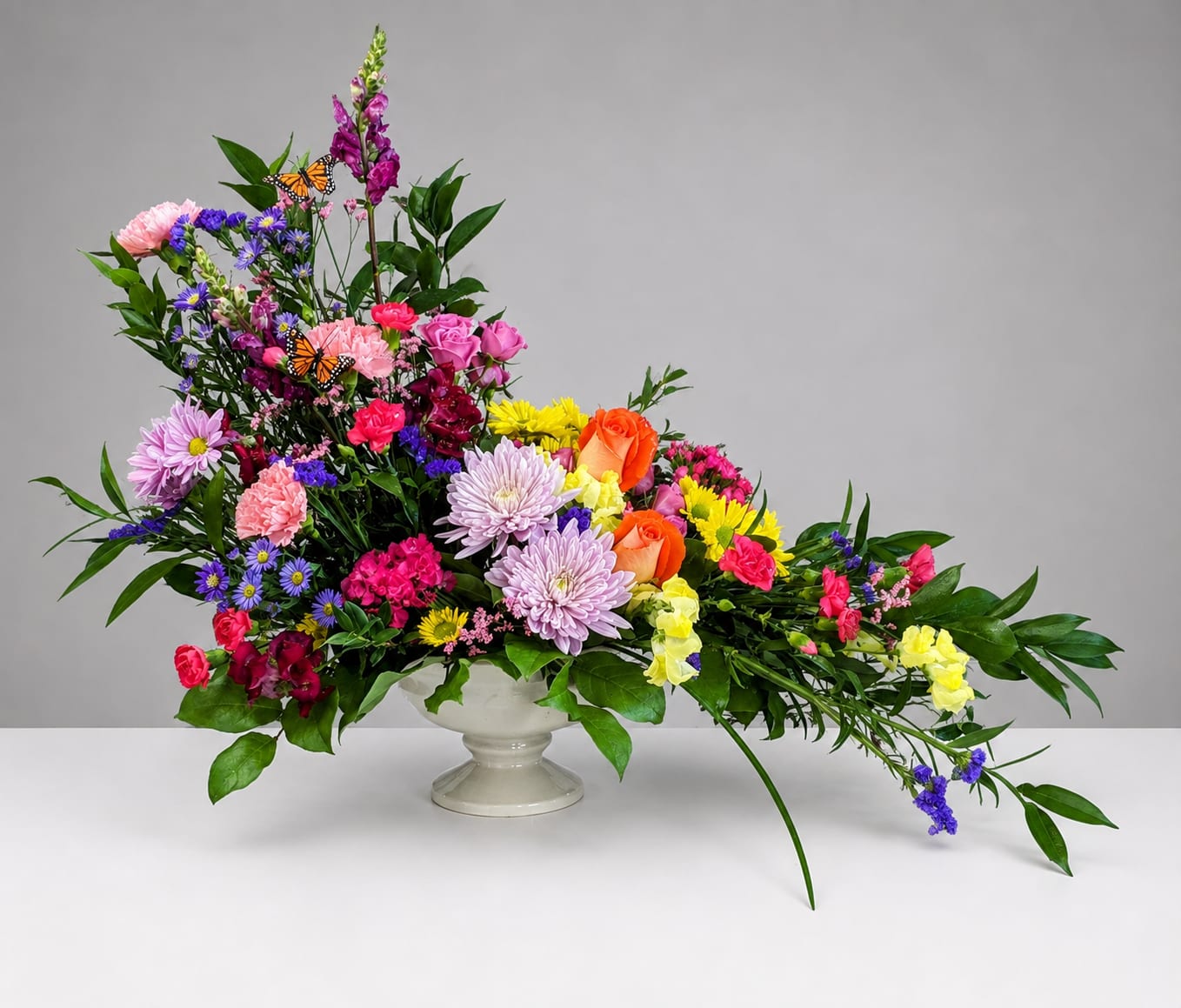 Colorful mixed flower arrangement in a white pedestal vase