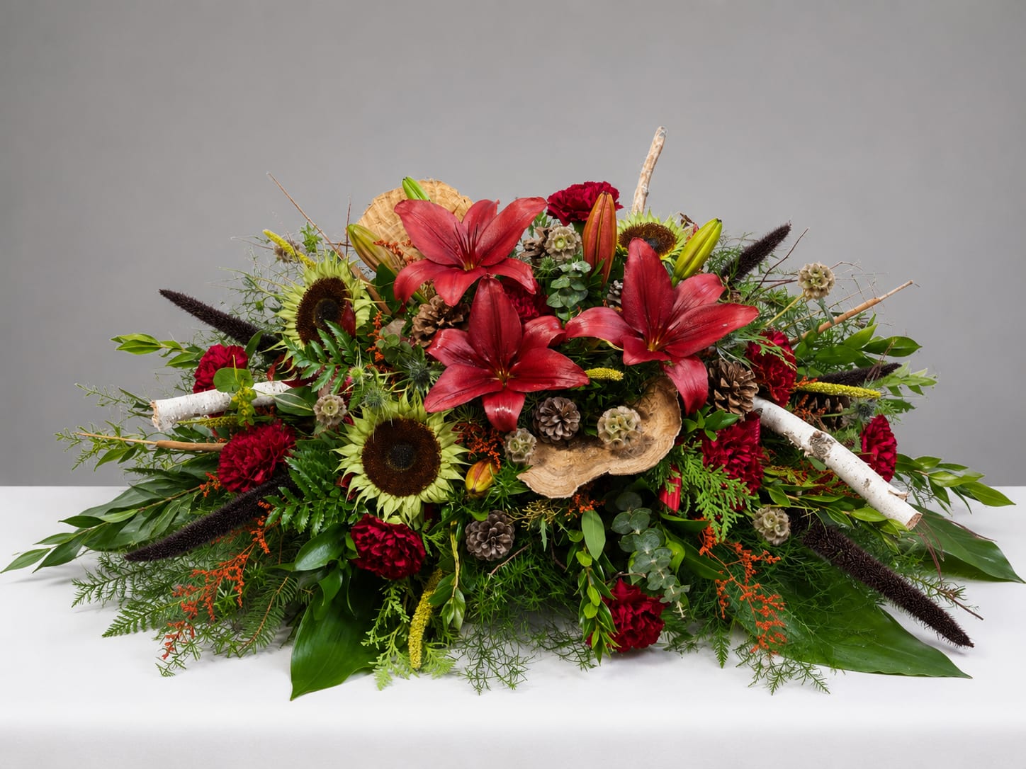 Large floral arrangement with red lilies, sunflowers, and red carnations