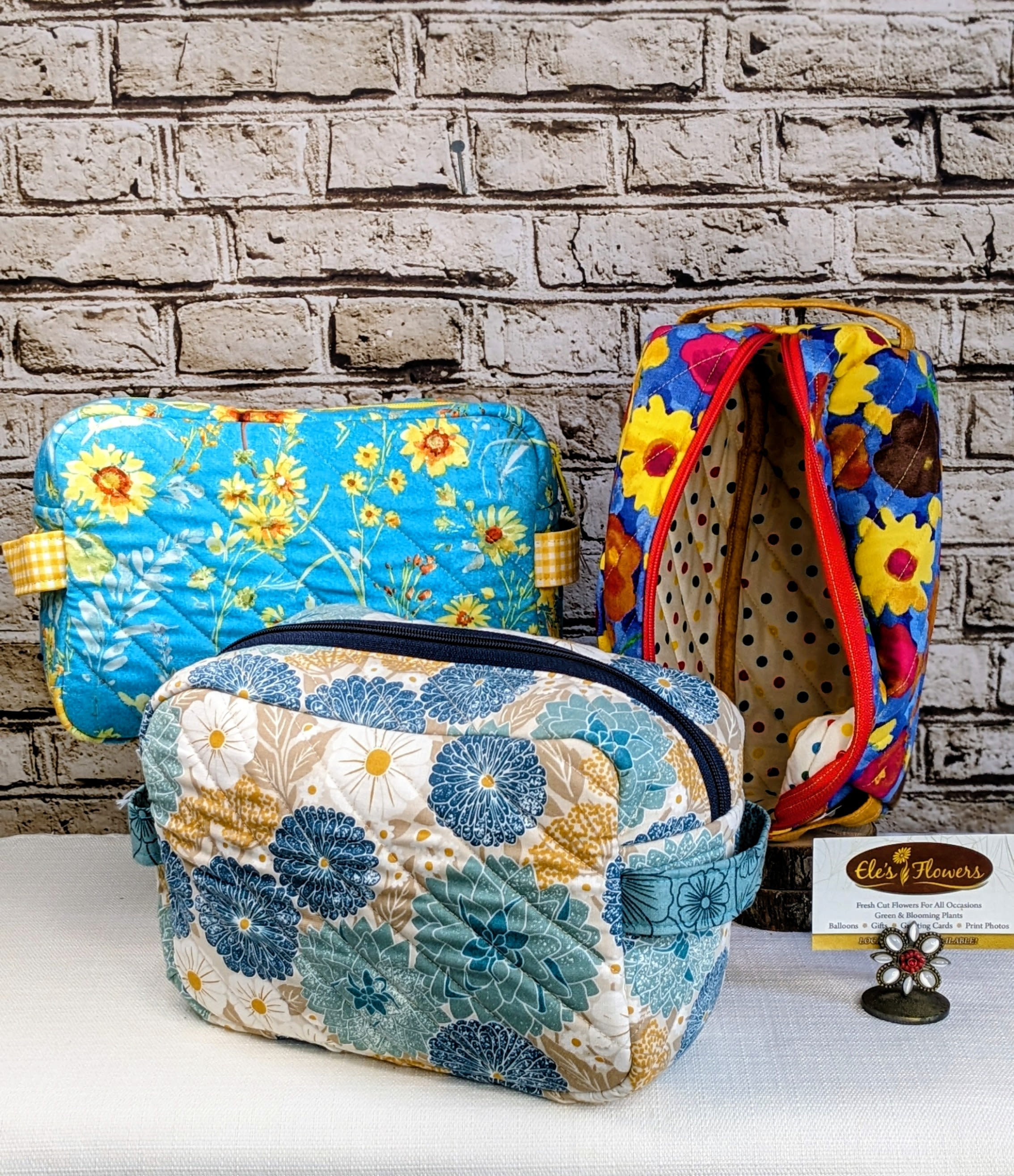 Three floral-patterned quilted zip pouches on a table