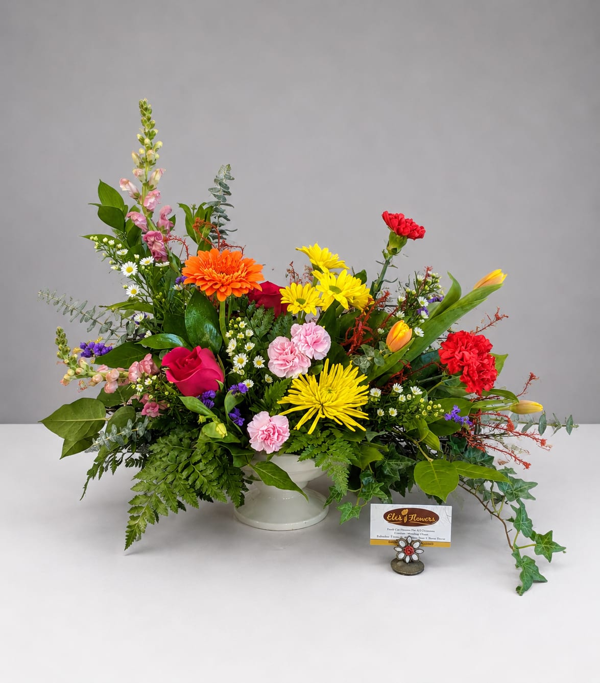 Colorful mixed flower arrangement in a white pedestal vase
