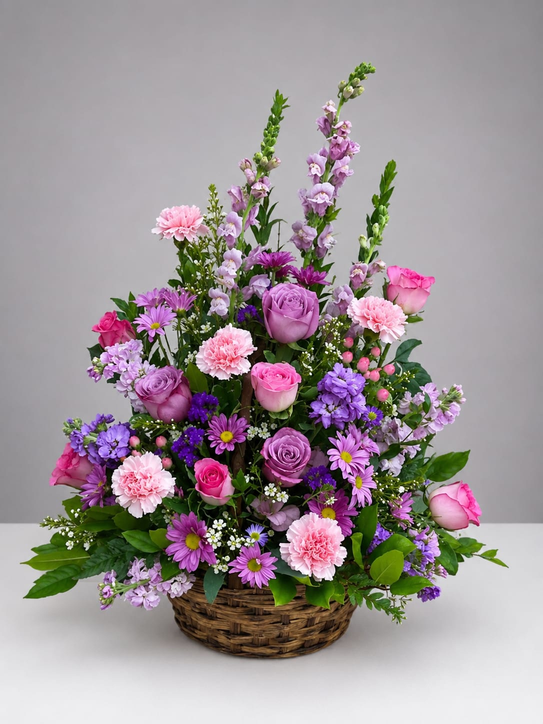 Pink and purple mixed flower arrangement in a wicker basket