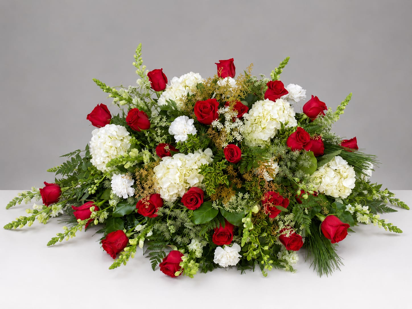 Red roses and white hydrangeas arranged in a low, wide spray