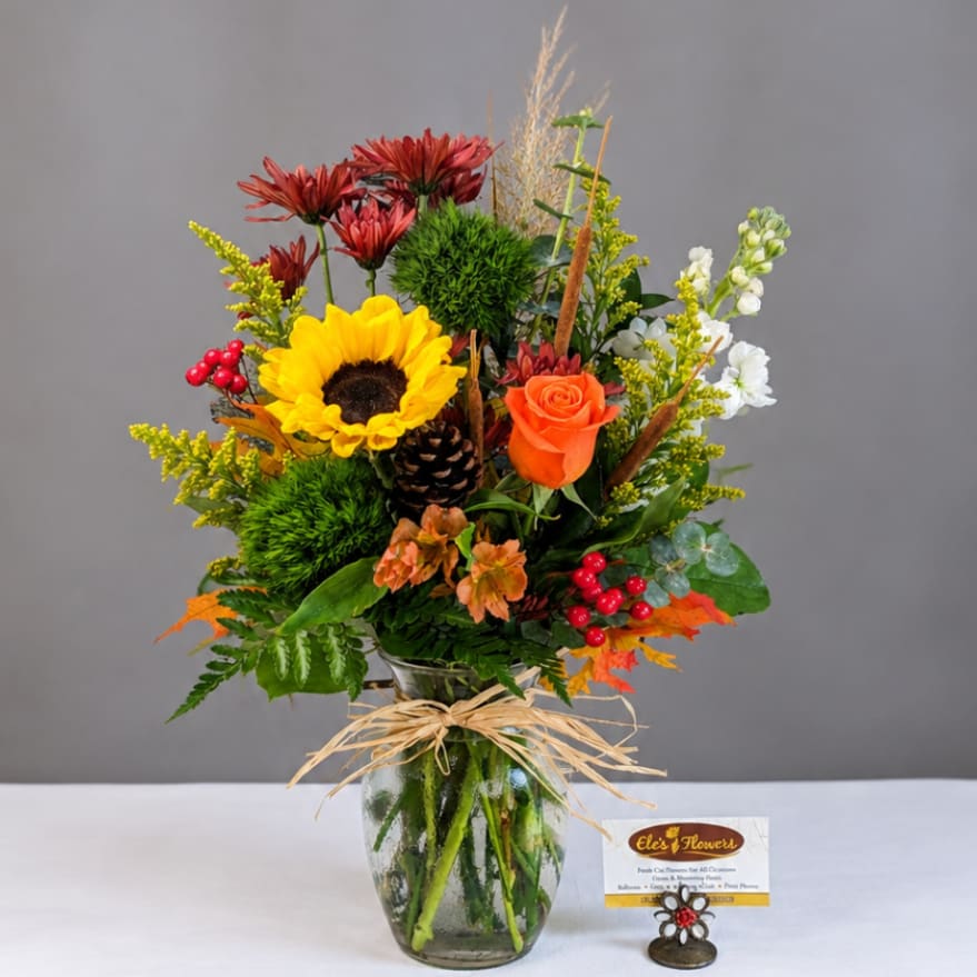 Mixed bouquet in a glass vase with a sunflower and orange rose