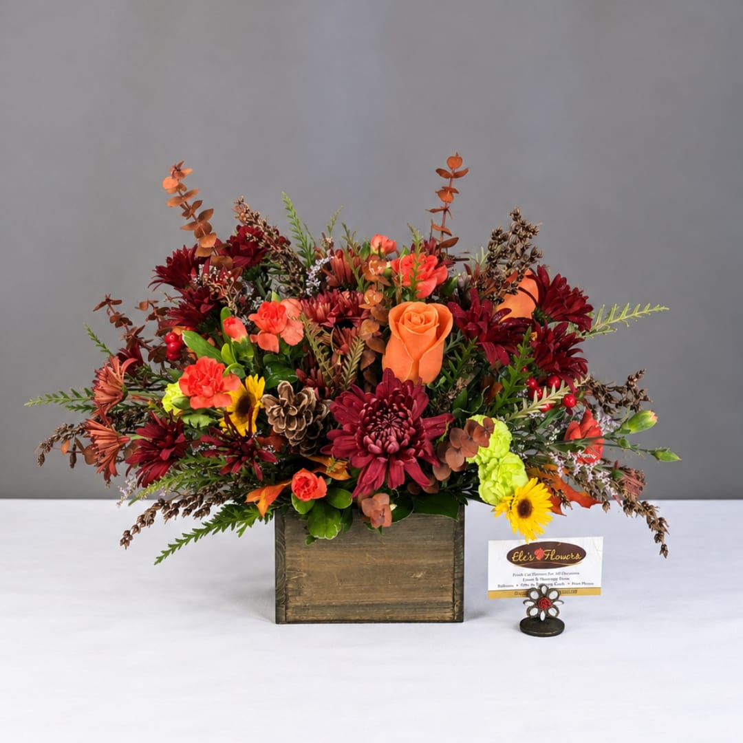 Autumn floral arrangement in a wooden box with orange and burgundy blooms