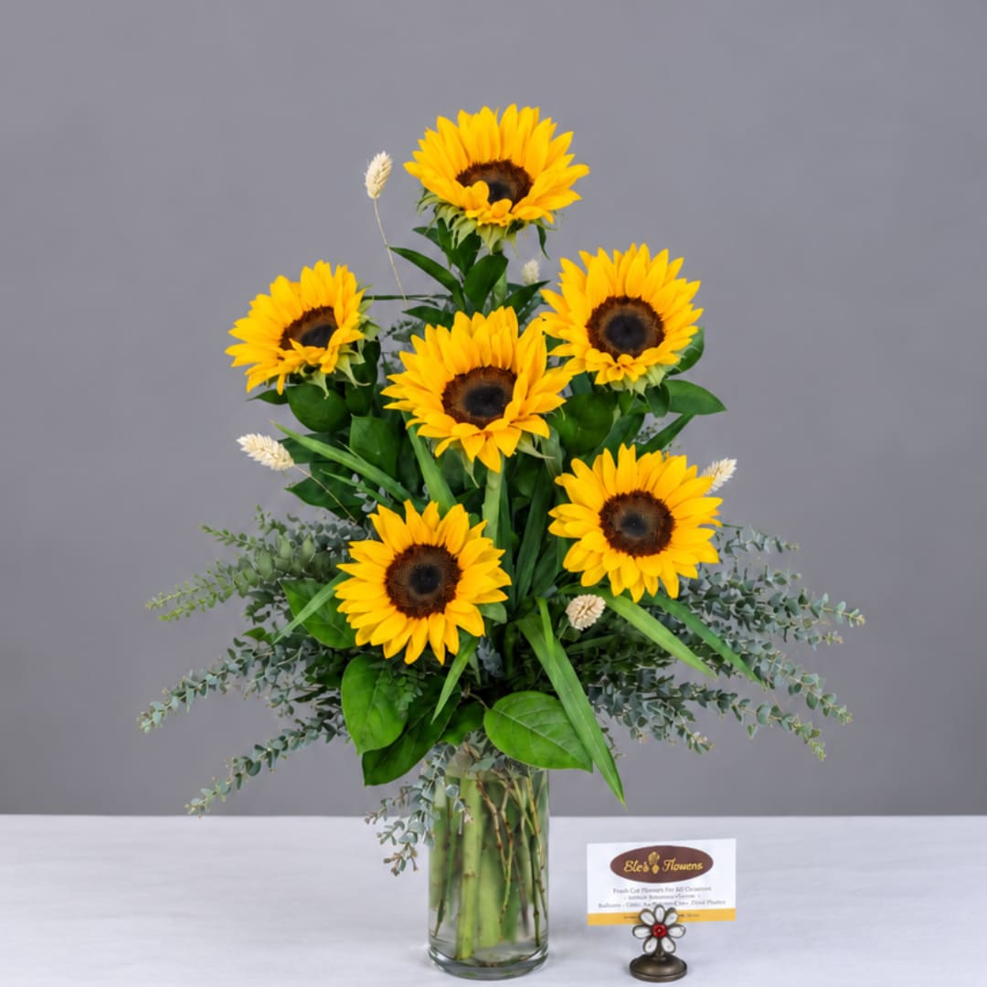 Sunflower arrangement in a clear glass vase with greenery