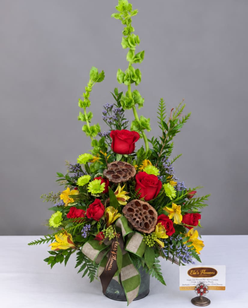 Tall mixed flower arrangement with red roses and yellow blooms in a vase